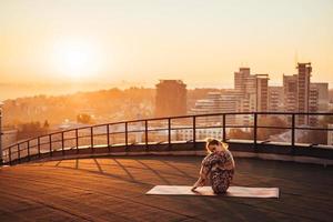 donna fare yoga su il tetto di un' grattacielo nel grande città. foto