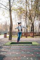 contento scuola ragazza salto su un' piccolo trampolino nel il parco foto