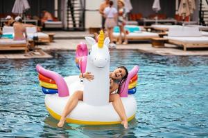 donna su gonfiabile unicorno giocattolo materasso galleggiante nel piscina. foto