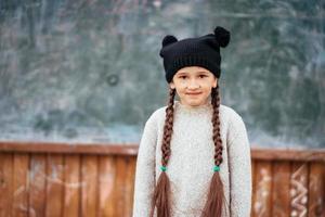 poco ragazza nel un' cappello in posa su il sfondo di il scuola lavagna foto