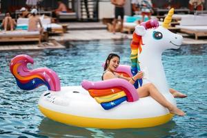 donna su gonfiabile unicorno giocattolo materasso galleggiante nel piscina. foto