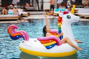 donna su gonfiabile unicorno giocattolo materasso galleggiante nel piscina. foto