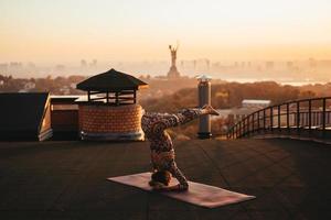 donna fare yoga su il tetto di un' grattacielo nel grande città. foto