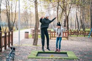 mamma e sua figlia salto insieme su trampolino nel autunno parco foto