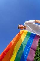 un' giovane donna si sviluppa un' arcobaleno bandiera contro il cielo foto