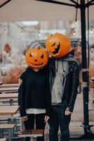 un' tipo e un' ragazza con un' zucca teste in posa su il strada foto