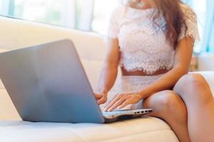 vista ravvicinata di mani femminili digitando sulla tastiera. foto ritagliata progetto di lavoro donna con il suo divano collocato laptop