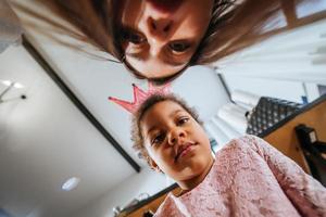 poco ragazza seduta su il pavimento smorfie a il telecamera foto