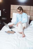 donna di affari che utilizza computer portatile nella camera di albergo foto