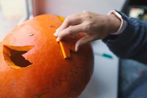 mano di un' giovane donna taglio su un' Halloween zucca foto