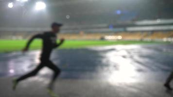 persone partire nel per gli sport a notte stadio nel piovoso tempo metereologico foto