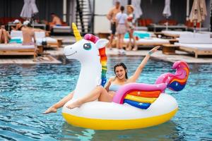 donna su gonfiabile unicorno giocattolo materasso galleggiante nel piscina. foto