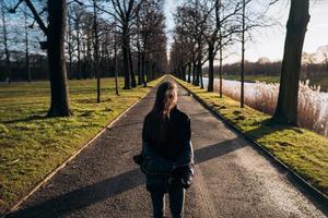 ritratto di un' brunetta ragazza avendo divertimento nel un' parco nel il raggi di il luminosa sole. foto