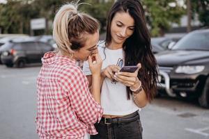 Due bellissimo giovane donne siamo guardare a un' smartphone foto