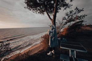 giovane donna prende immagini di il mare tramonto di smartphone foto