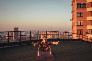 donna fare yoga su il tetto di un' grattacielo nel grande città. foto