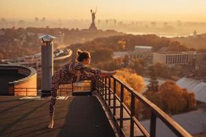 donna fare yoga su il tetto di un' grattacielo nel grande città. foto