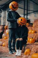 un' tipo e un' ragazza con un' zucca teste in posa su il strada foto