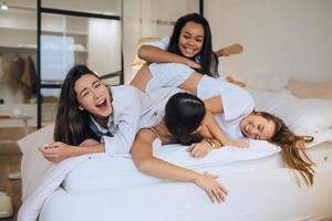 positivo giovane ragazze donne amici in casa su letto a il gallina festa a casa. foto