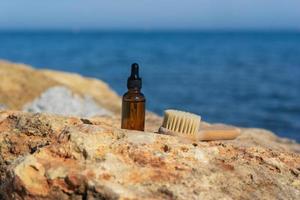 un' naturale essenziale olio o siero nel un' Marrone contagocce bottiglia in piedi su il pietre a il mare foto