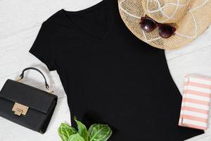 t camicia nero. maglietta modello piatto posare con estate Accessori. cappello, Borsa e occhiali da sole su di legno pavimento sfondo. copia spazio. modello vuoto tela. davanti superiore Visualizza. foto