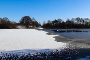 neve coperto congelato lago paesaggio nel settentrionale Europa su un' soleggiato giorno. foto