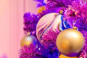 viola neon Natale albero decorato wth oro palline e ghirlanda. festivo saluto carta per Natale e nuovo anno. foto