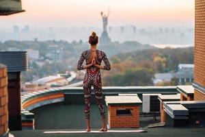 donna fare yoga su il tetto di un' grattacielo nel grande città. foto