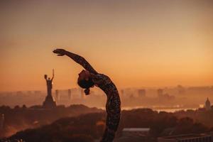 donna fare yoga su il tetto di un' grattacielo nel grande città. foto