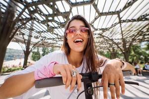 giovane bellissimo donna stuzzicando e mostrando lingua a telecamera nel parco foto