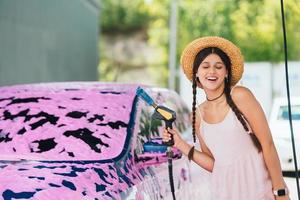 donna con tubo flessibile sta di auto coperto nel rosa schiuma foto