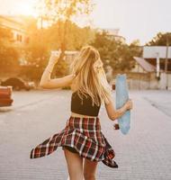 giovane ragazza con un' skateboard su un' auto parco. foto