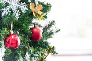 Natale e nuovo anno vacanza concetto. avvicinamento Natale albero decorazione con nastri palle e ornamenti al di sopra di bianca mattone parete e bokeh foto