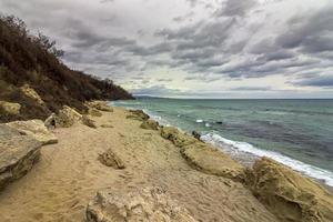 panoramico Visualizza a un' pietroso spiaggia con nuvoloso cielo foto