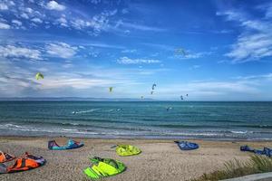 kitesurfisti fare surf il vento su onde su un' luminosa soleggiato estate giorno foto