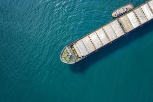 aereo tiro di un' carico nave si avvicina porta con Aiuto di rimorchio nave foto