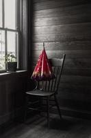 immagine seppia con ombrello rosso seduto sulla sedia dalla finestra