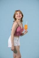 contento asiatico donna nel estate casuale Abiti con un' bicchiere di fresco frutta succo bevanda su pastello blu sfondo foto