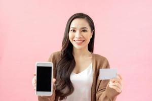 commercio elettronico, shopping e stile di vita concetto. asiatico ragazza trovato eccezionale applicazione per in linea acquisti, ordine tracciamento, Tenere mobile Telefono, mostrare schermo e credito carta foto