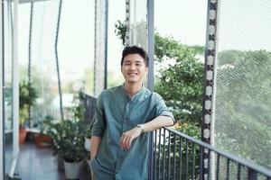 giovane asiatico tipo in attesa e pendente nel mano rotaia foto