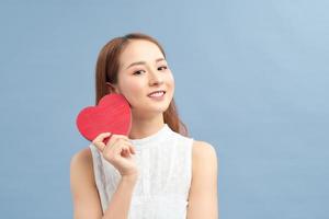 contento donna hold rosso cuore. bellissimo femmina modello in posa su isolato blu sfondo. foto