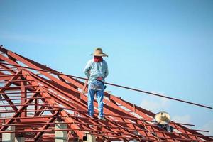 lavoratori del saldatore che installano la struttura del telaio in acciaio del tetto della casa in un cantiere edile foto