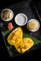 Mango appiccicoso Riso, Noce di cocco latte, ghiaccio crema e macarons su un' nero piatto popolare tailandese dolci nel estate