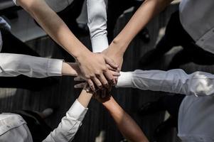 vicino su di giovane uomini d'affari mettere loro mani insieme. pila di mani concetto di unità e lavoro di squadra. foto