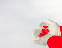 femmina mani nel a maglia bianca guanti hold un' seta rosso cuore su un' nevoso sfondo. concetto di amore e san valentino. foto