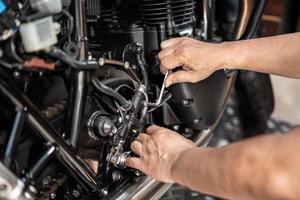 meccanico utilizzando un' esadecimale chiave o allen chiave inglese per rimuovere motociclo posteriore idraulico freno pompa, Lavorando nel box auto .Manutenzione e riparazione motociclo concetto .selettivo messa a fuoco foto