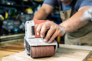 falegname Lavorando con cintura levigatrice lucidatura su di legno nel laboratorio ,Fai da te creatore e la lavorazione del legno concetto. selettivo messa a fuoco foto