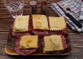 italiano gnocco fritto con salame su rustico di legno tavolo. sostituto per pane fatto con fritte Impasto. foto