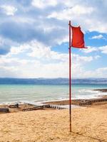 rosso bandiera su spiaggia di morto mare nel ventoso inverno giorno foto