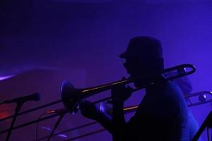 silhouette di un' jazz musicista nel un' debolmente illuminato club foto